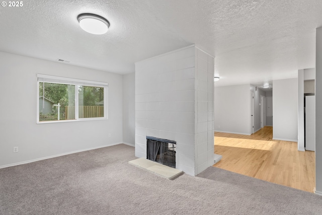 unfurnished living room with light carpet, a textured ceiling, and a multi sided fireplace