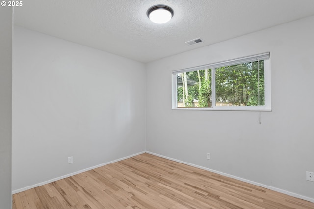 spare room featuring a textured ceiling and light wood-type flooring