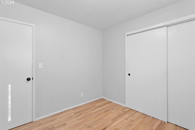 unfurnished bedroom with light hardwood / wood-style floors, a closet, and a textured ceiling