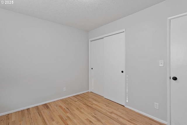 unfurnished bedroom featuring a closet, a textured ceiling, and light hardwood / wood-style flooring