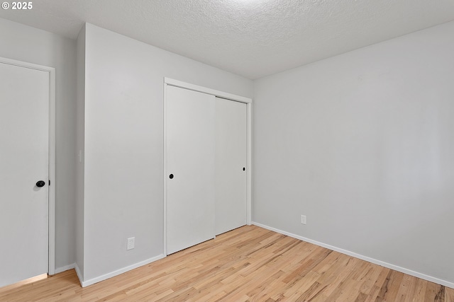 unfurnished bedroom featuring a closet, a textured ceiling, and light wood-type flooring