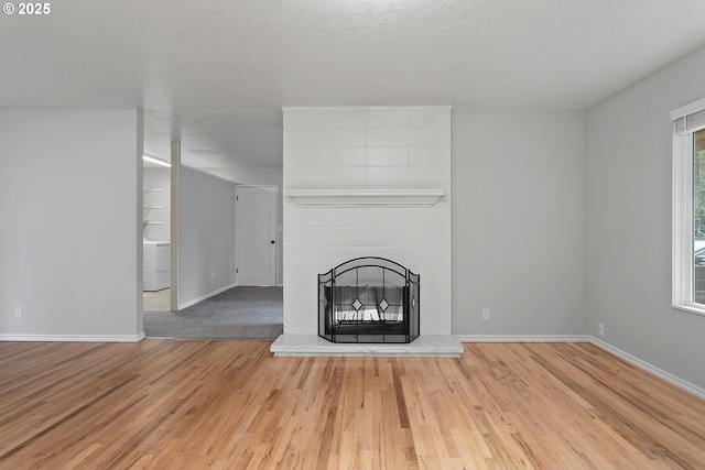 unfurnished living room with washer / dryer, wood-type flooring, a large fireplace, and a textured ceiling