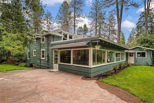 54 W 31st Ave, Eugene, OR 97405 - view of front of property featuring a front yard, a chimney, a patio area, and a sunroom