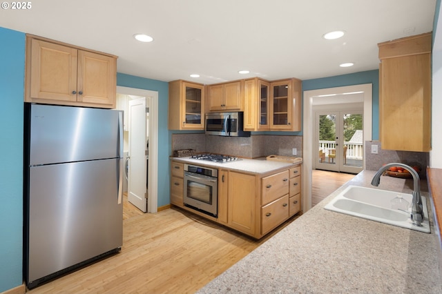 54 W 31st Ave, Eugene, OR 97405 - kitchen featuring appliances with stainless steel finishes, decorative backsplash, light wood finished floors, glass insert cabinets, and light countertops
