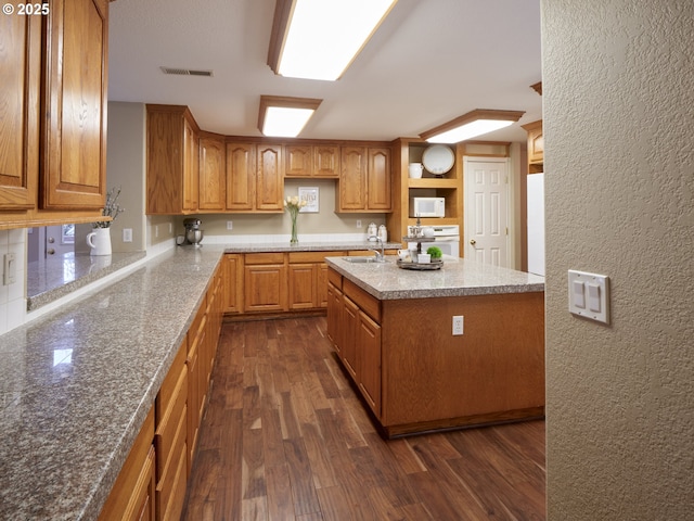 2605 NE 189th St, Ridgefield, WA 98642 - kitchen with a textured wall, visible vents, dark wood-style floors, brown cabinetry, and an island with sink