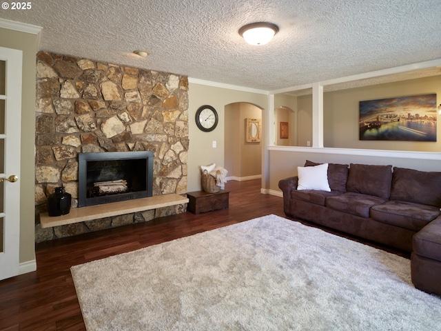 2605 NE 189th St, Ridgefield, WA 98642 - living room with arched walkways, dark wood-style flooring, crown molding, a fireplace, and a textured ceiling