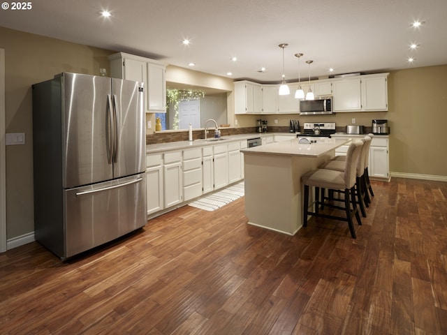 2605 NE 189th St, Ridgefield, WA 98642 - kitchen with dark wood finished floors, a kitchen island, appliances with stainless steel finishes, white cabinetry, and a sink