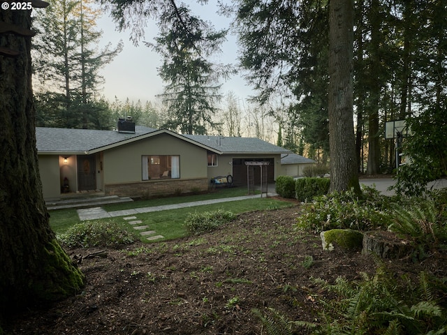 rear view of house with a chimney, a lawn, and stucco siding