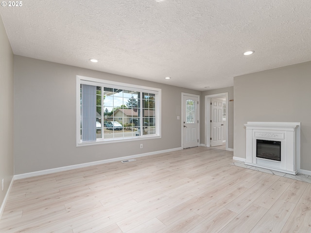 11421 SE Pardee St, Portland, OR 97266 - unfurnished living room with a textured ceiling, light wood-style flooring, a glass covered fireplace, recessed lighting, and baseboards