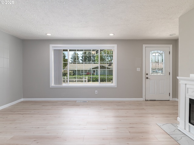 11421 SE Pardee St, Portland, OR 97266 - foyer entrance featuring healthy amount of natural light, light wood-style floors, a textured ceiling, a glass covered fireplace, and recessed lighting