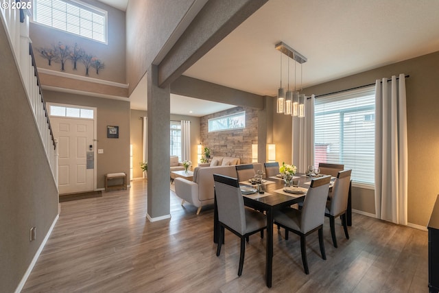 dining area with hardwood / wood-style flooring, a high ceiling, and a healthy amount of sunlight