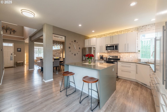 kitchen featuring a kitchen bar, white cabinetry, appliances with stainless steel finishes, and a center island