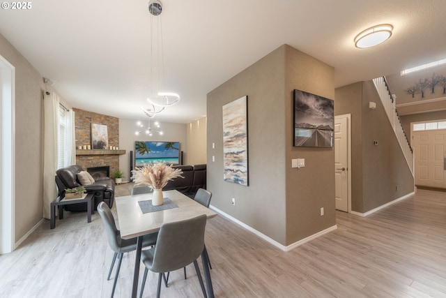 dining area with a notable chandelier, light hardwood / wood-style floors, and a fireplace