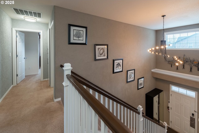 corridor with light colored carpet and an inviting chandelier