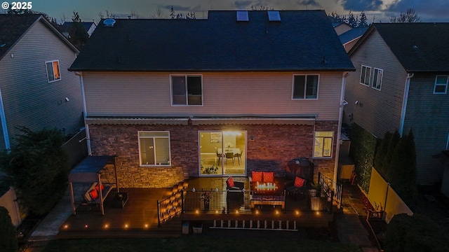 back house at dusk with a deck