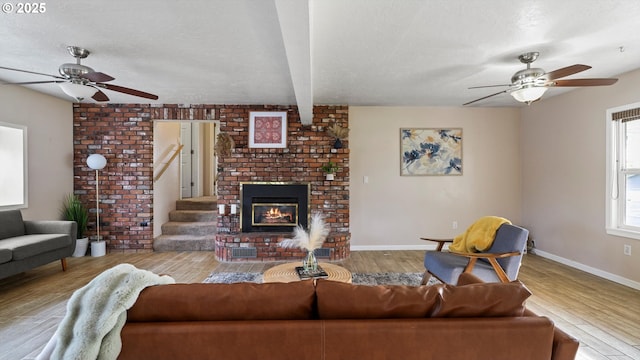 1060 SW 7th St, Hermiston, OR 97838 - living room with ceiling fan, wood finished floors, a brick fireplace, baseboards, and a textured ceiling