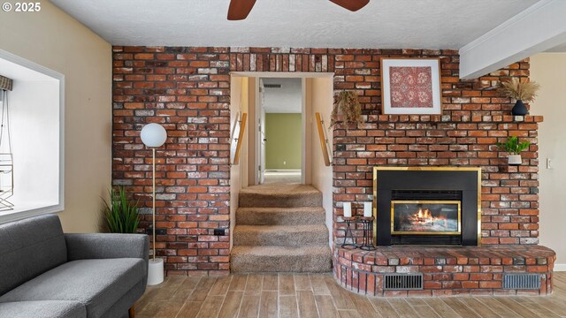1060 SW 7th St, Hermiston, OR 97838 - unfurnished living room with wood finish floors, ceiling fan, a brick fireplace, stairway, and a textured ceiling