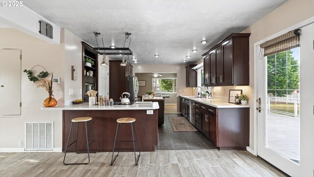 1060 SW 7th St, Hermiston, OR 97838 - kitchen with a sink, dark brown cabinets, wood tiled floors, a breakfast bar area, and light countertops