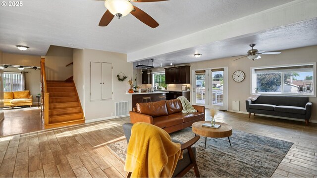 1060 SW 7th St, Hermiston, OR 97838 - living room with a ceiling fan, light wood-type flooring, stairs, plenty of natural light, and a textured ceiling
