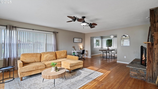 1060 SW 7th St, Hermiston, OR 97838 - living room featuring a ceiling fan, wood finished floors, a stone fireplace, and baseboards
