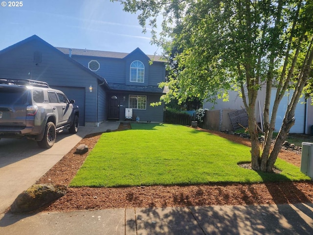 traditional-style home featuring an attached garage, fence, driveway, and a front yard