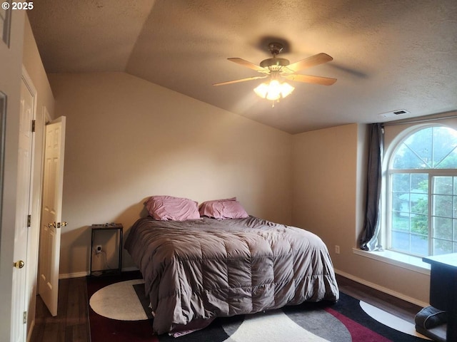 bedroom with a textured ceiling, baseboards, wood finished floors, and visible vents