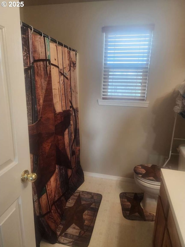 bathroom featuring baseboards, a shower with shower curtain, toilet, and vanity