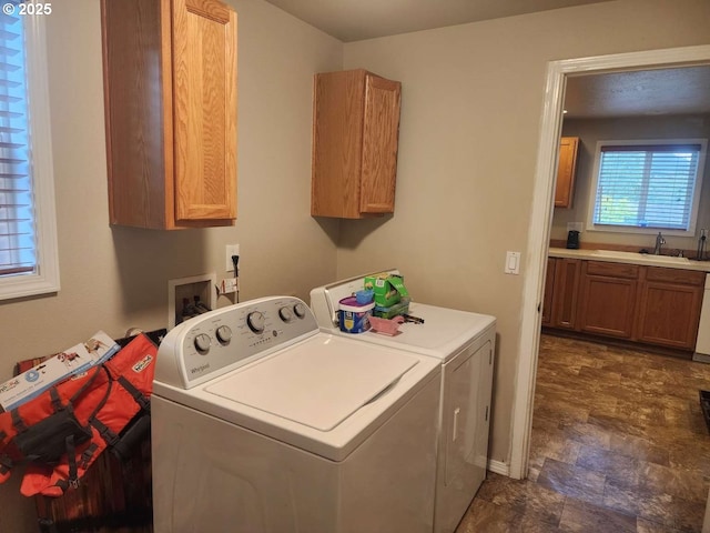 clothes washing area featuring a sink, washing machine and dryer, and cabinet space