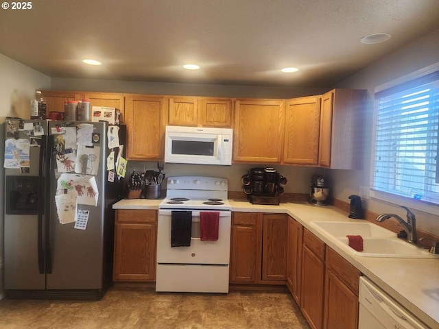 kitchen featuring a sink, light countertops, recessed lighting, and white appliances