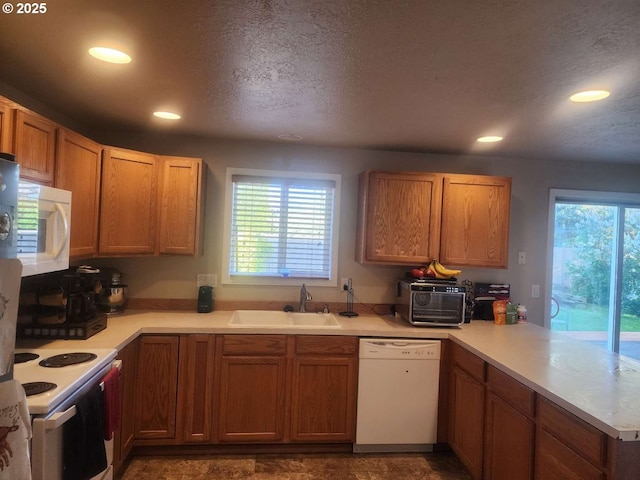 kitchen with a sink, plenty of natural light, a peninsula, and white appliances