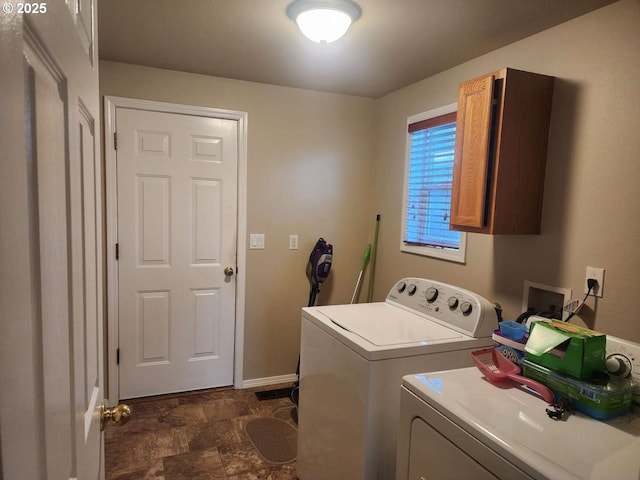 laundry room with baseboards, stone finish flooring, cabinet space, and washing machine and dryer