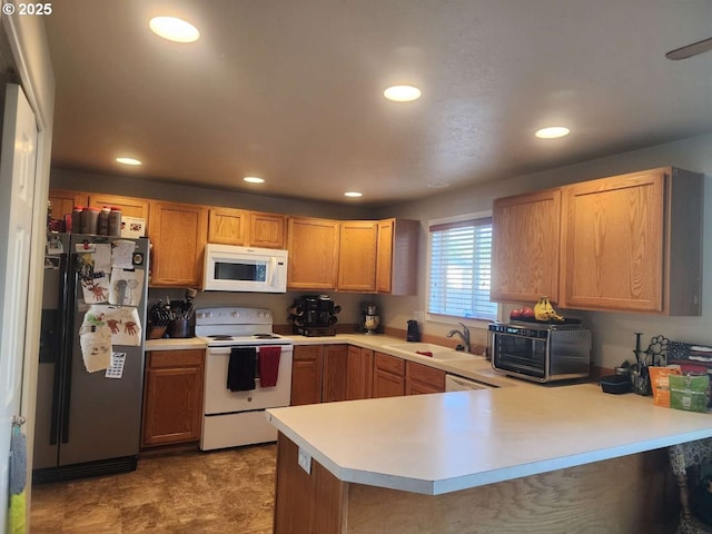 kitchen featuring a peninsula, white appliances, recessed lighting, light countertops, and a sink
