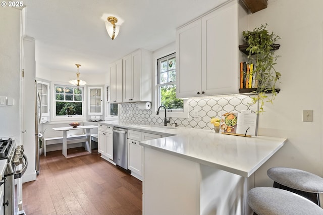 1710 SE 42nd Ave, Portland, OR 97215 - kitchen with a sink, appliances with stainless steel finishes, a peninsula, dark wood-style flooring, and decorative backsplash