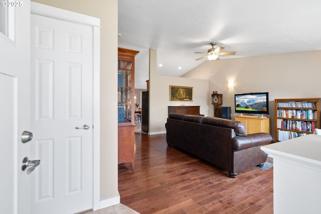 living room featuring a ceiling fan, vaulted ceiling, baseboards, and wood finished floors