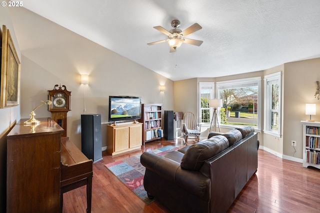 living room with dark wood finished floors, lofted ceiling, ceiling fan, a textured ceiling, and baseboards