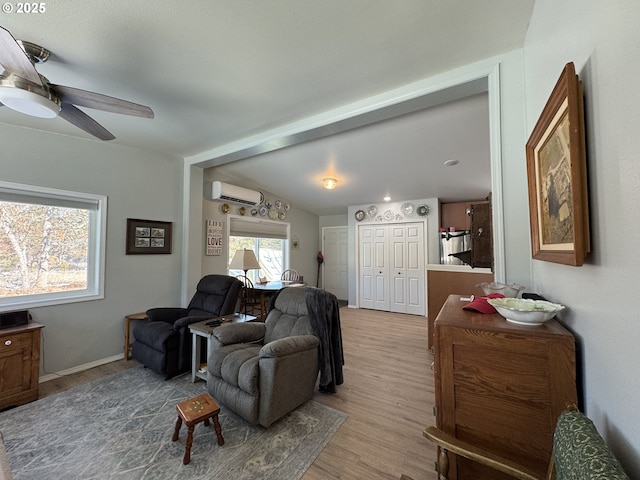 living room with a wall mounted air conditioner, ceiling fan, and light wood-type flooring