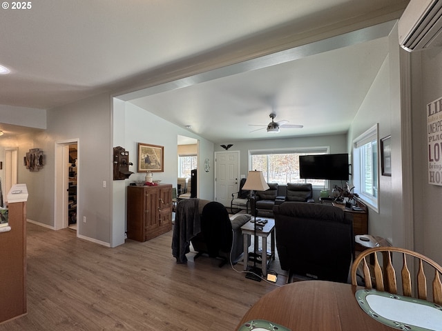 living room featuring hardwood / wood-style flooring, a wall mounted air conditioner, and ceiling fan