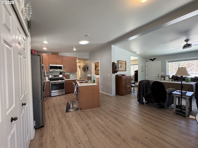 kitchen with stainless steel appliances, ceiling fan, sink, and light hardwood / wood-style floors