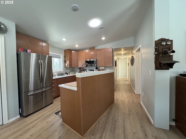 kitchen featuring lofted ceiling, stainless steel appliances, sink, and light wood-type flooring