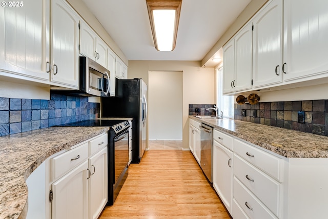 kitchen featuring a sink, stainless steel appliances, light wood-style flooring, and white cabinetry