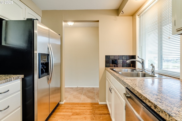 kitchen featuring tasteful backsplash, light wood-type flooring, appliances with stainless steel finishes, white cabinetry, and a sink