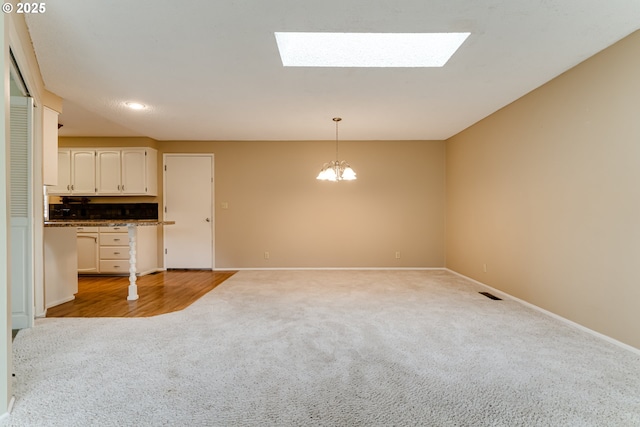 interior space with light carpet, a skylight, and baseboards