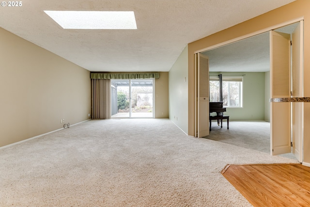 unfurnished living room featuring plenty of natural light, carpet, a skylight, and a textured ceiling