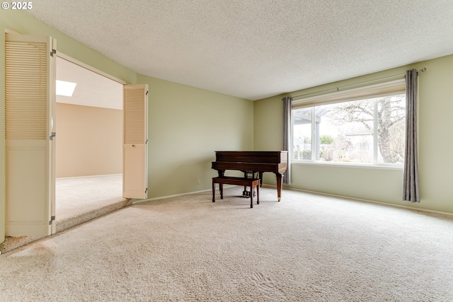 living area featuring a skylight, carpet floors, and a textured ceiling