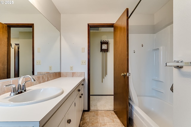 bathroom featuring shower / bathtub combination, vanity, stone finish flooring, and baseboards