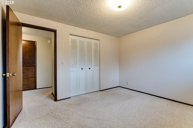 unfurnished bedroom featuring baseboards, a closet, carpet floors, and a textured ceiling