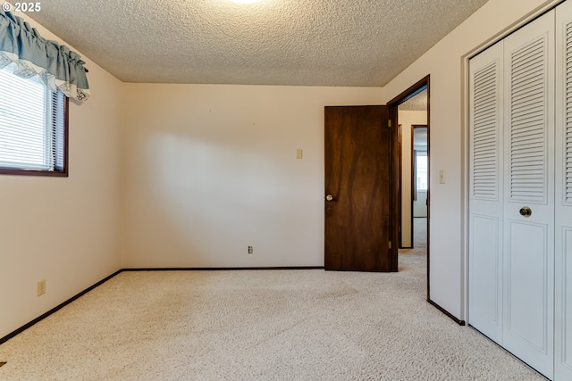 unfurnished bedroom featuring a closet, a textured ceiling, carpet, and baseboards