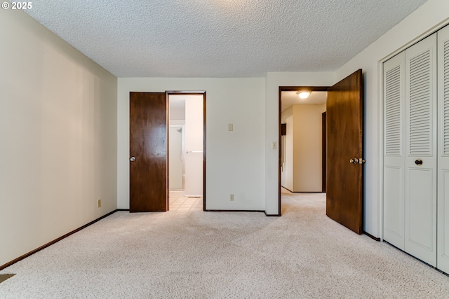 unfurnished bedroom featuring a textured ceiling, baseboards, a closet, and light carpet