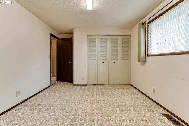 unfurnished bedroom featuring a closet, visible vents, a textured ceiling, and baseboards