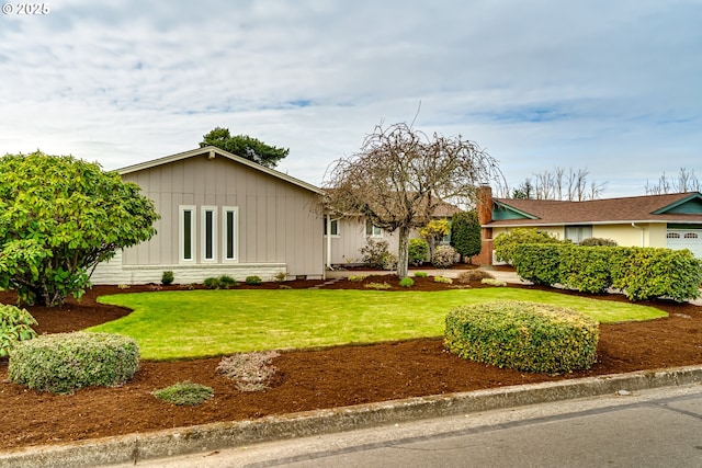 view of front of house with an attached garage, board and batten siding, and a front yard